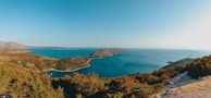 A panoramic view of the island’s green hills meeting the deep blue sea under a bright sky.