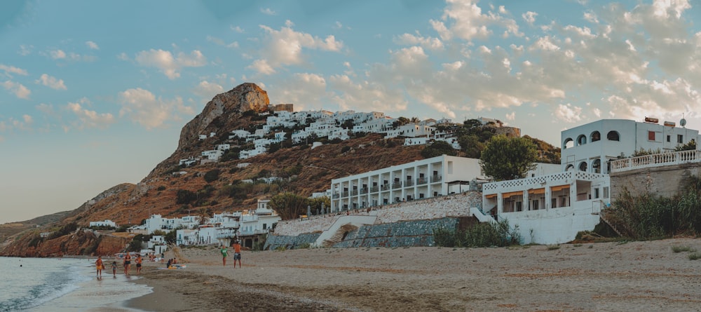 white concrete building near mountain under white clouds and blue sky during daytime