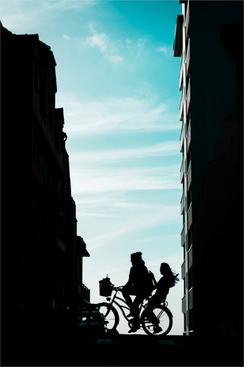 silhouette of man riding bicycle on road between high rise buildings during daytime