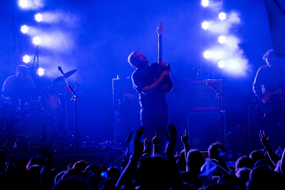 man in black t-shirt playing guitar on stage