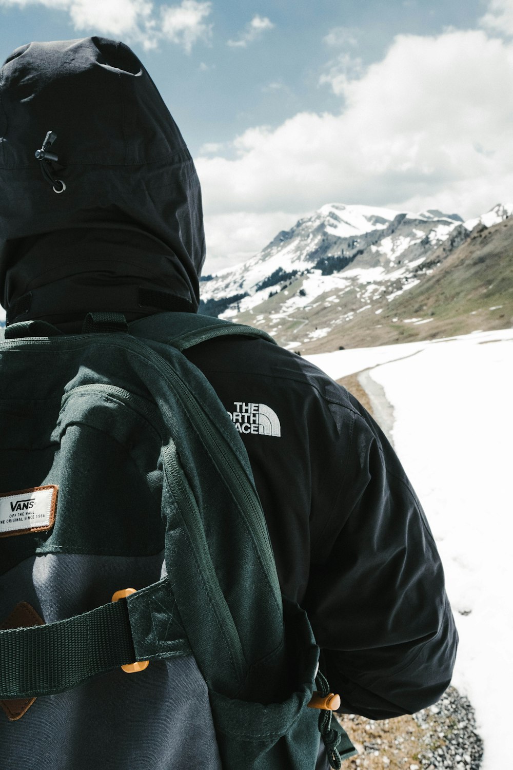 Persona in giacca nera e zaino nero in piedi su terreno coperto di neve durante il giorno