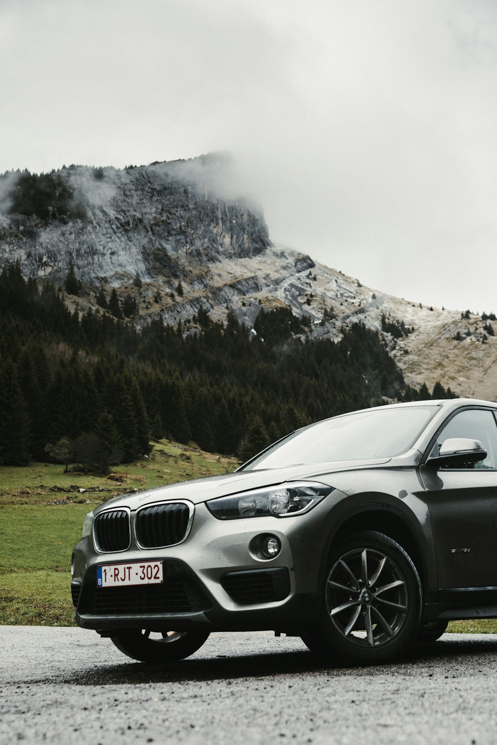 BMW M 3 negro en un campo de hierba verde cerca de la montaña cubierta de nieve durante el día