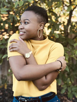 A happy person measuring their waist with a tape measure in a natural setting.