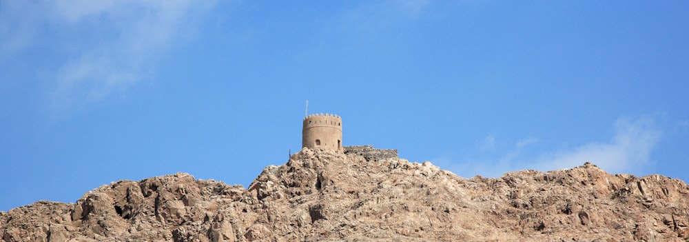 gray concrete castle on rocky hill under blue sky during daytime