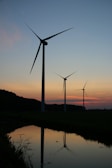 wind turbines on green grass field during sunset