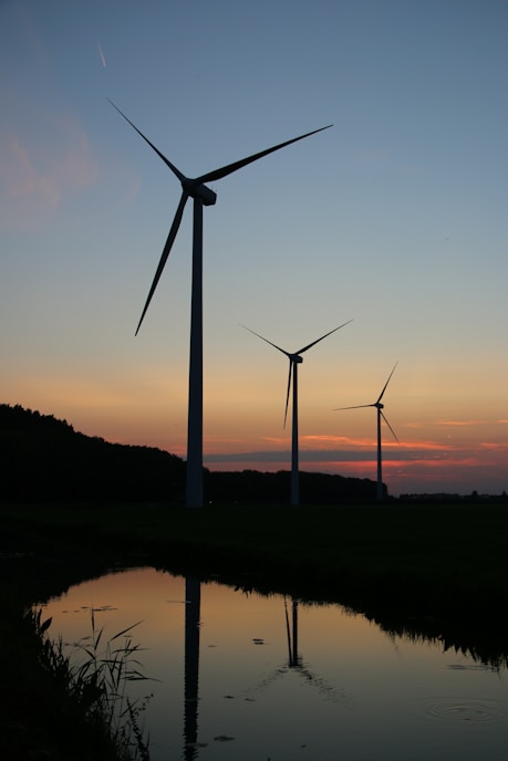 wind turbines on green grass field during sunset