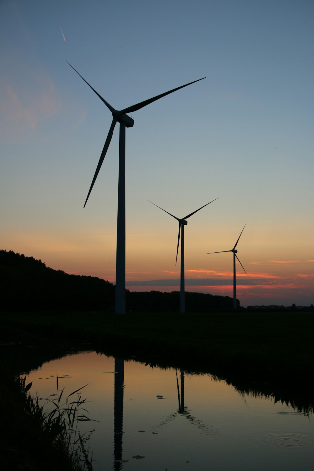 wind turbines on green grass field during sunset