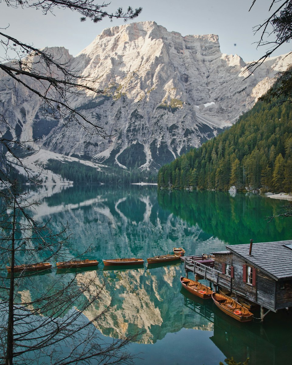 The wooden boathouse on the shore of Lago di Braies with turquoise water and Dolomite peaks behind it