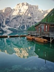 brown wooden house on green lake near snow covered mountain during daytime