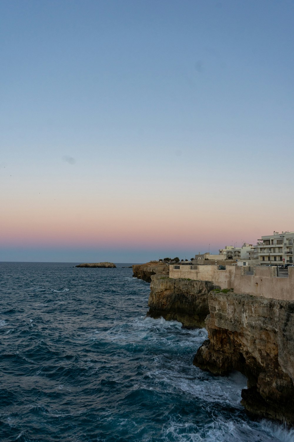 white concrete building on cliff by the sea during daytime