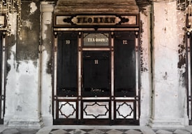 An ornate and historic looking storefront with dark wood panels and an overhead sign reading 'Florian'. The structure is flanked by two columns and features a section labeled 'Tea Room' above the center door, with faded walls showing signs of age and wear.