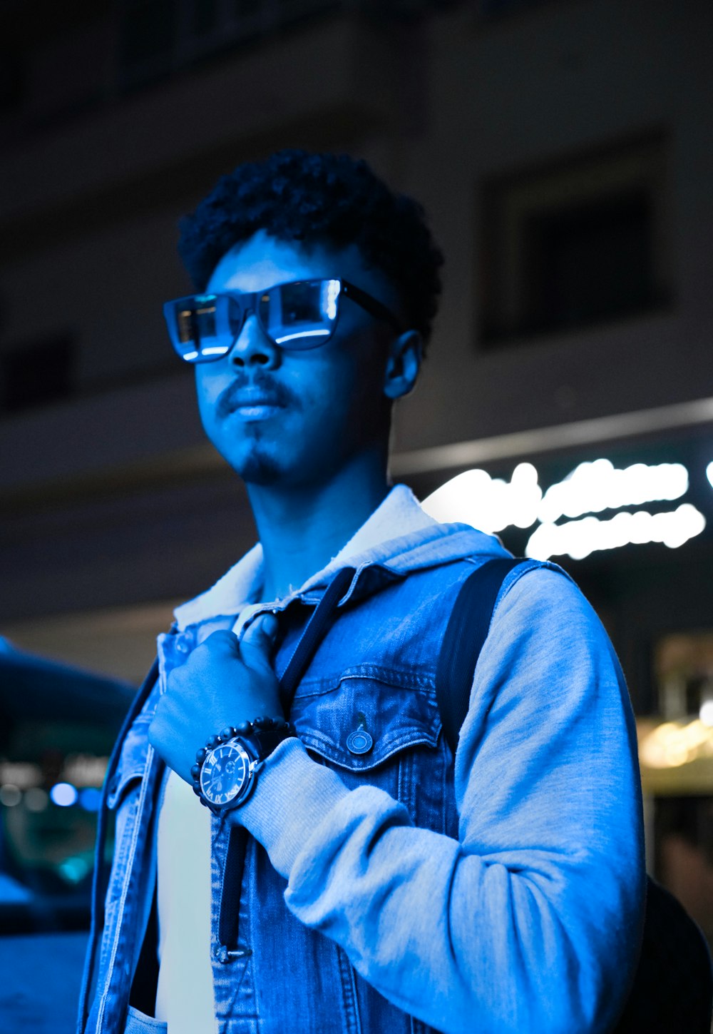 man in blue denim jacket wearing black framed eyeglasses
