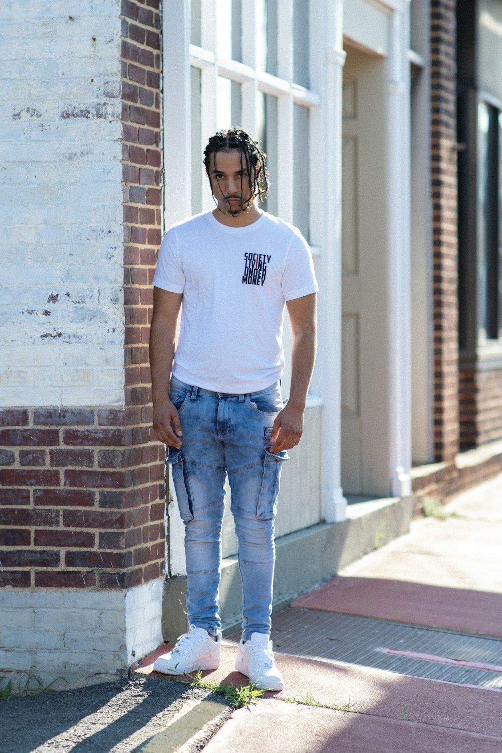 Man in neck t-shirt and blue denim jeans standing beside brown wall photo – Free Blue Image on Unsplash