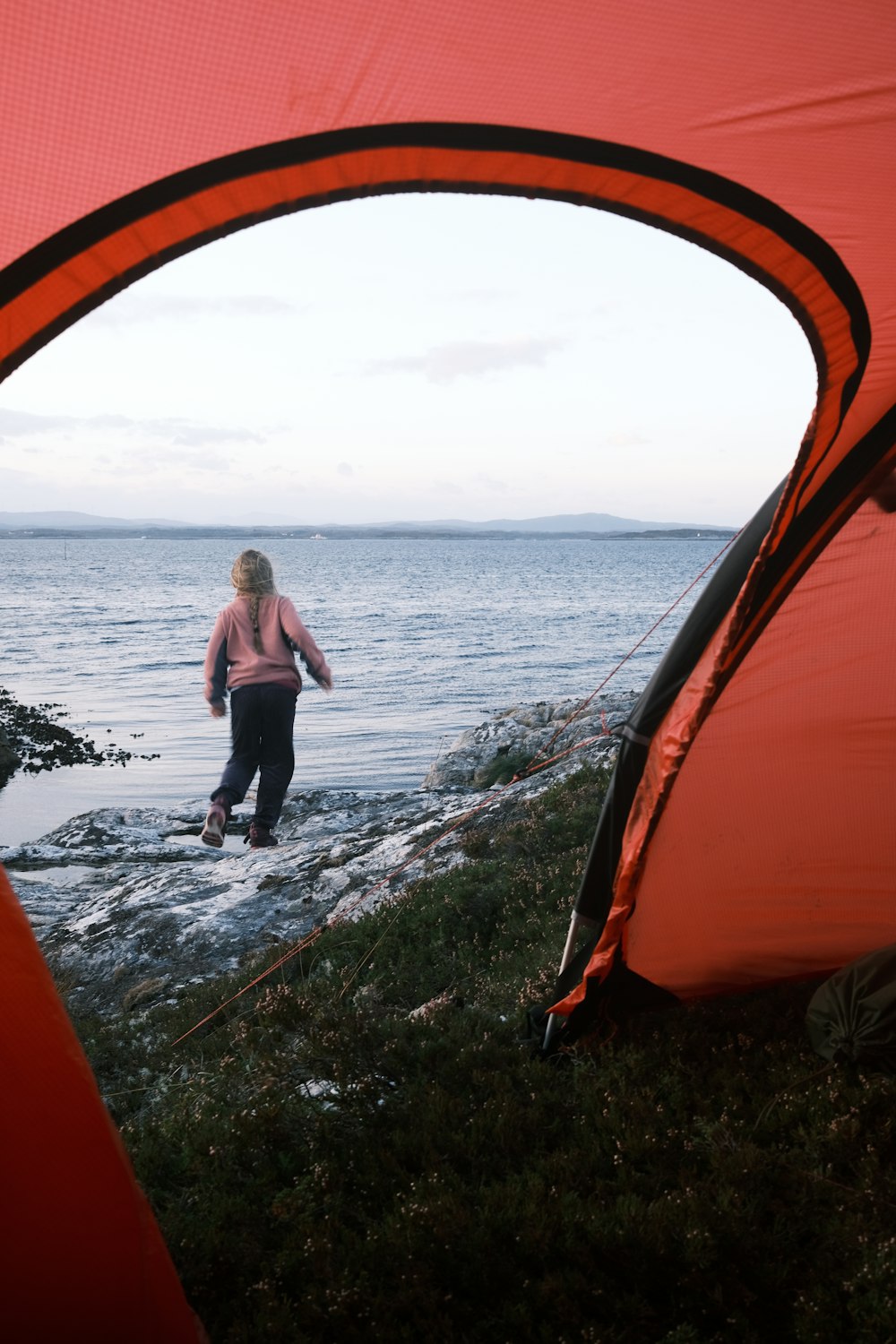 woman in black tank top and black pants standing on rocky shore during daytime