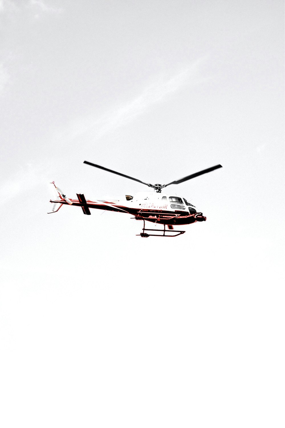 white and red helicopter flying in the sky