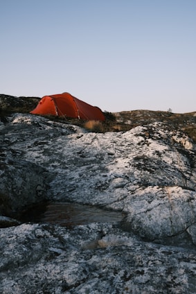 orange tent on rocky shore during daytime