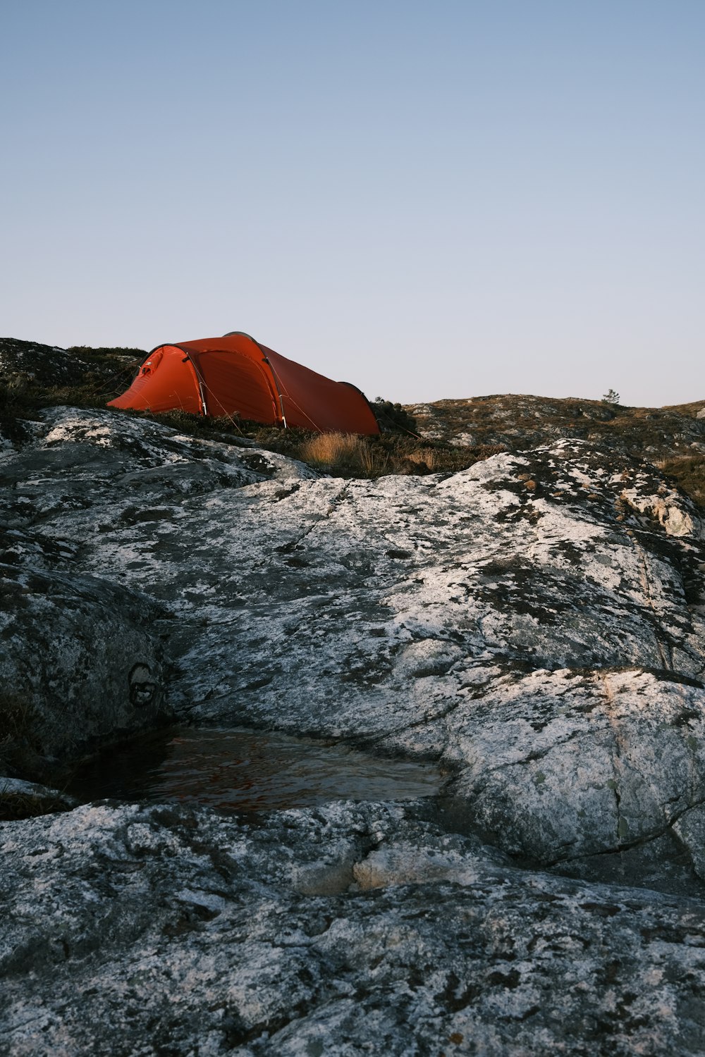 orange tent on rocky shore during daytime