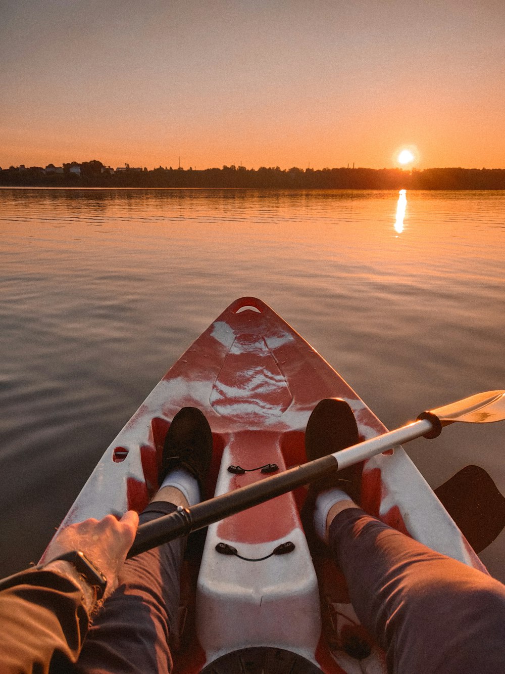 person in red kayak on lake during sunset