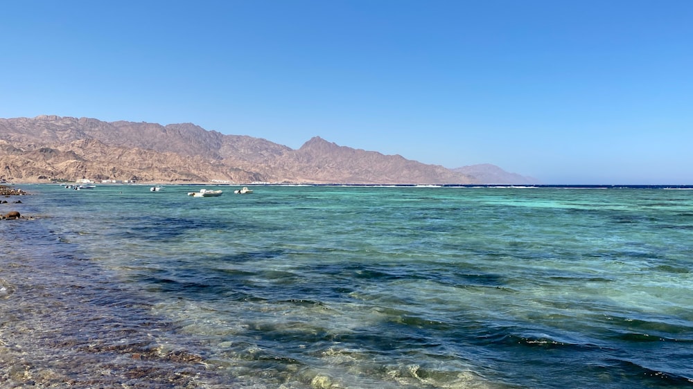 blue sea near mountain under blue sky during daytime