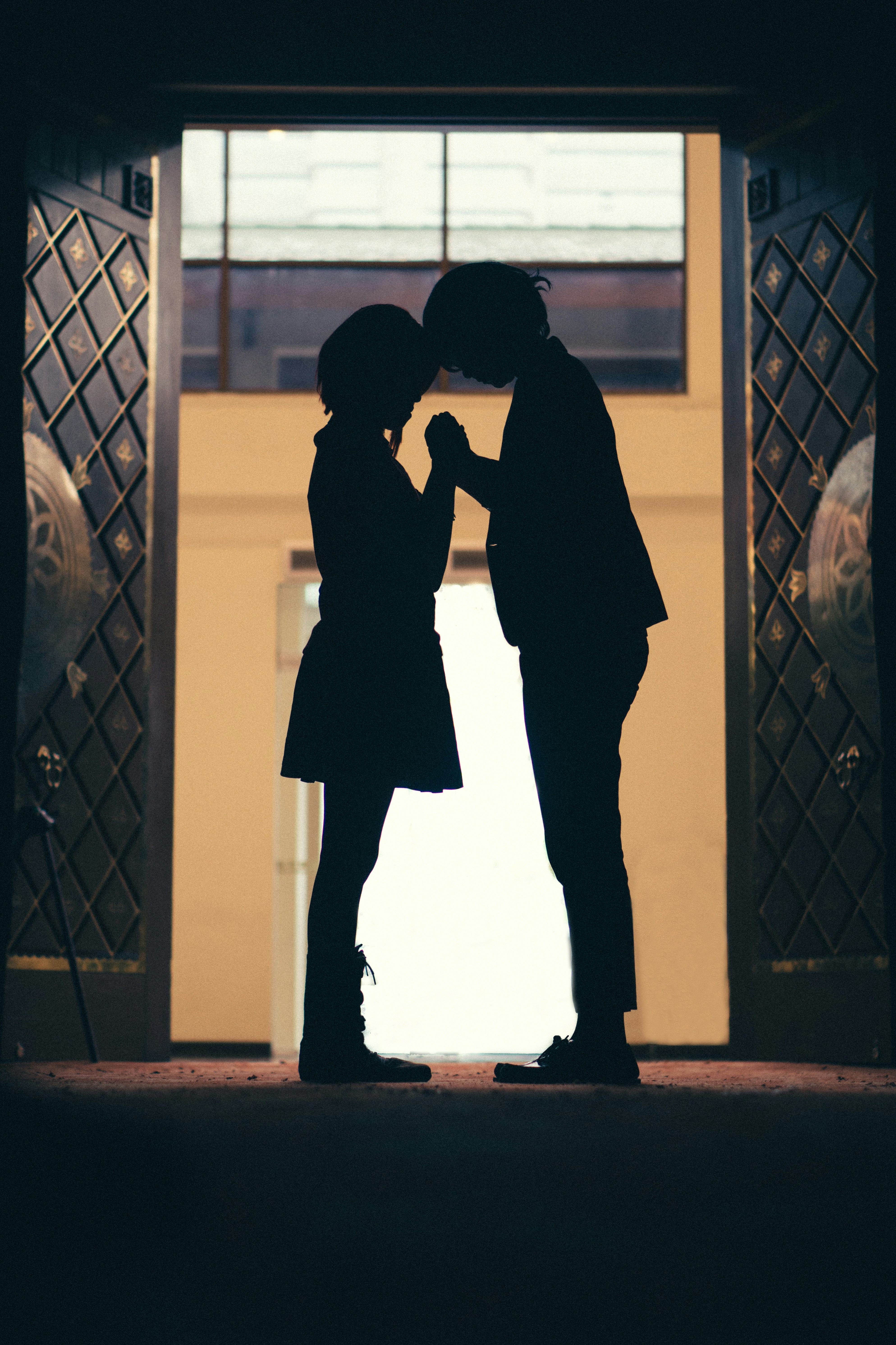 man and woman kissing in front of black metal gate