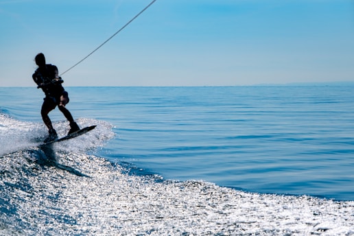 man in black wetsuit surfing on blue sea under blue sky during daytime