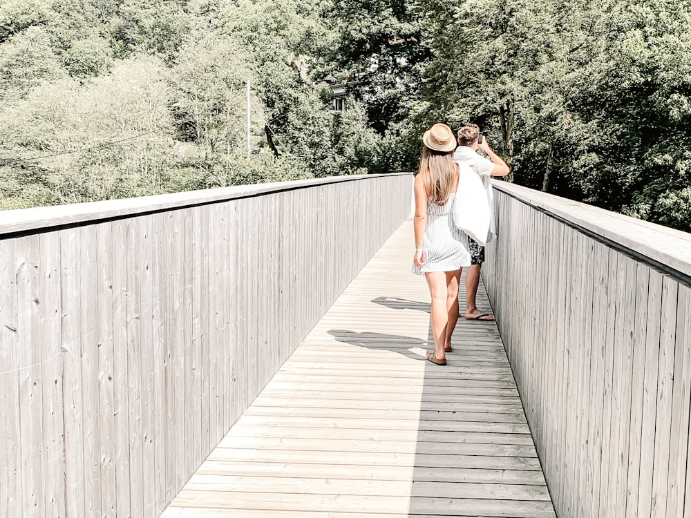 白いシャツと青いデニムのショートパンツを着た女性が昼間、木製の橋の上を歩く
