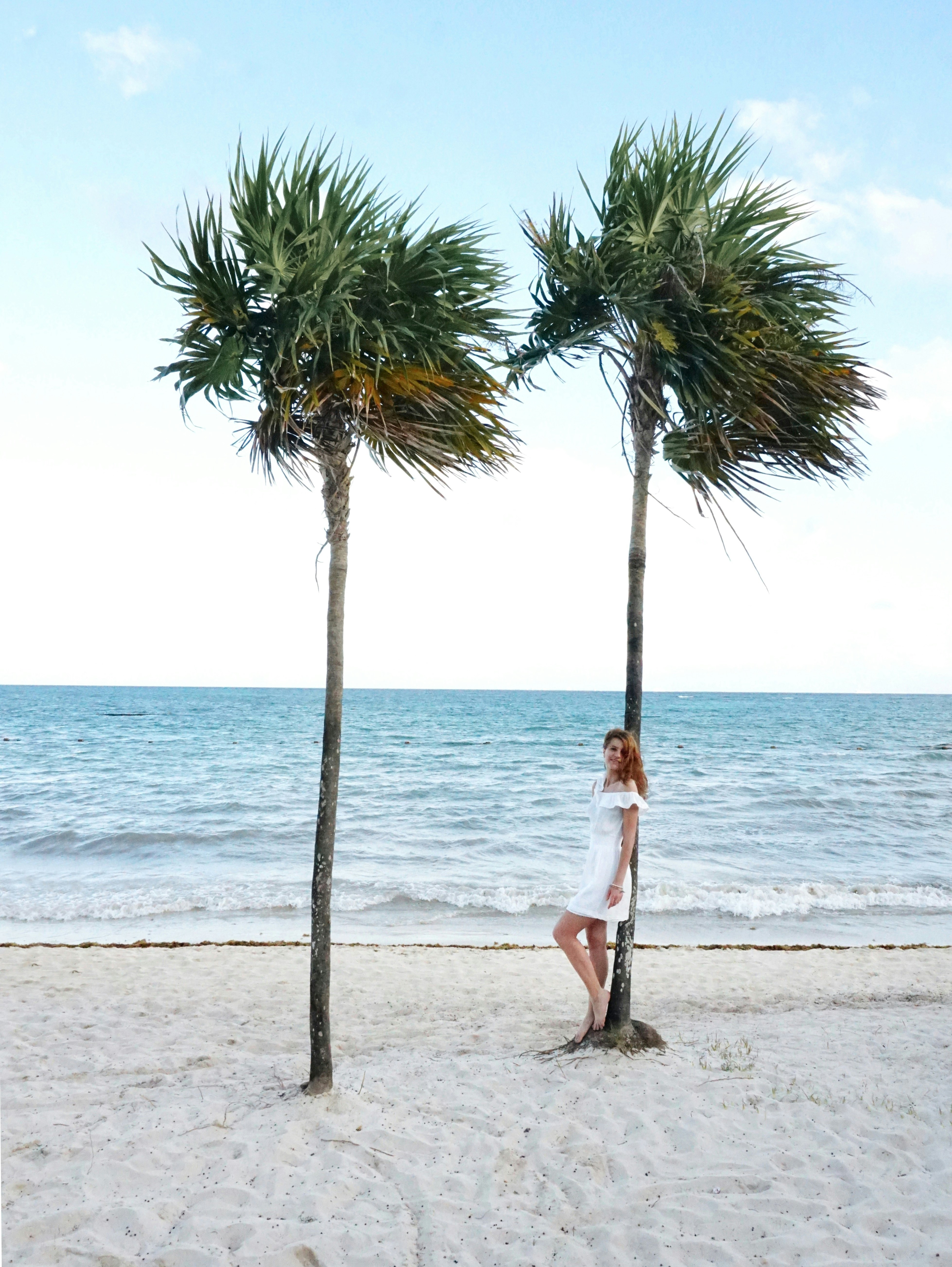 woman in white dress standing on beach during daytime