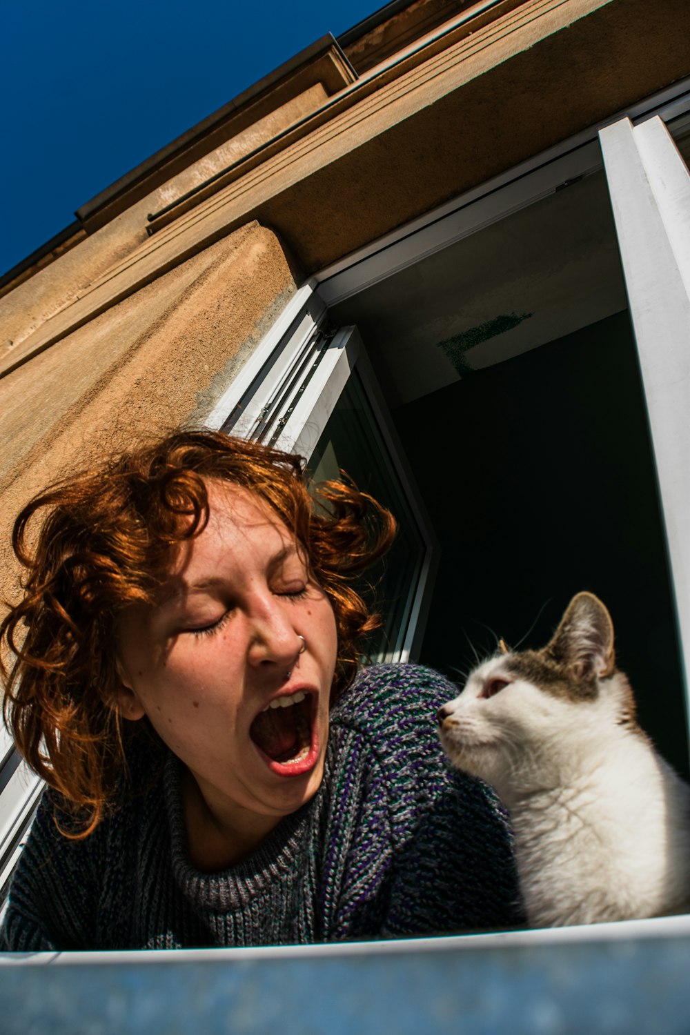 woman in black and white shirt smiling beside white and black cat