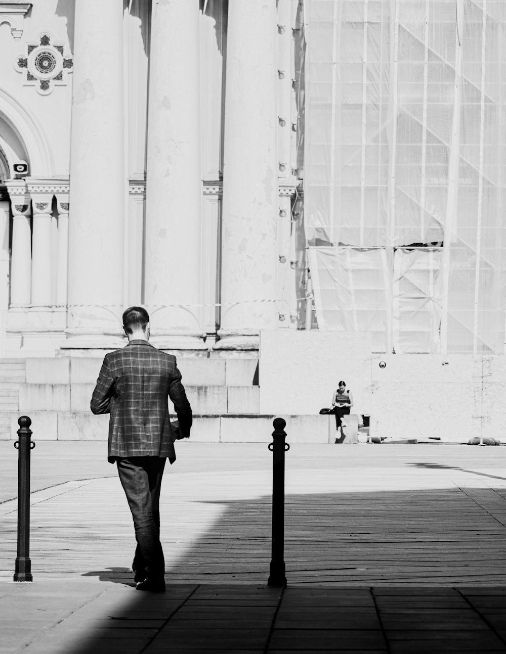 man in black and white checkered dress shirt standing on sidewalk during daytime