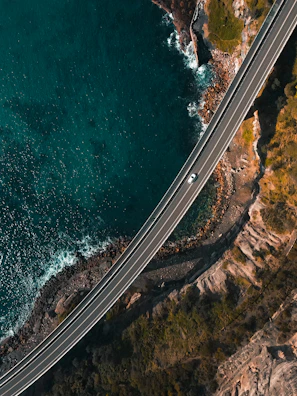 Wide shot of the camper driving along a winding coastal road.