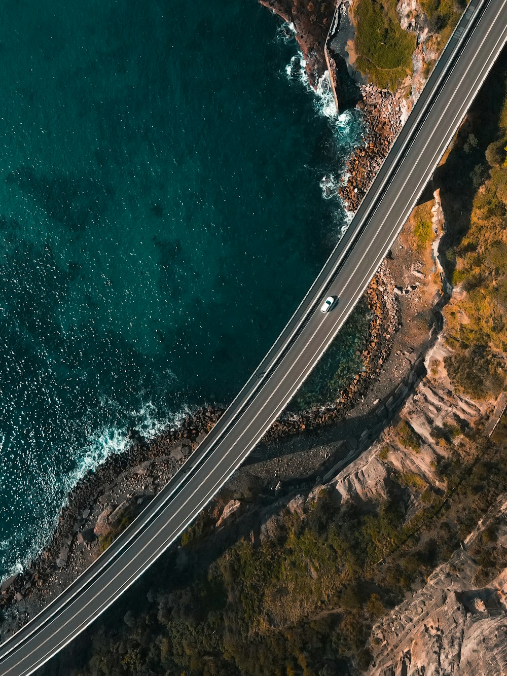 aerial view of road beside body of water during daytime