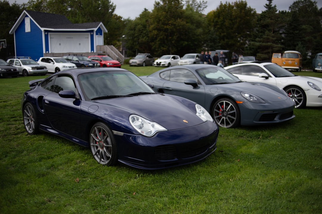 black porsche 911 parked on green grass field during daytime