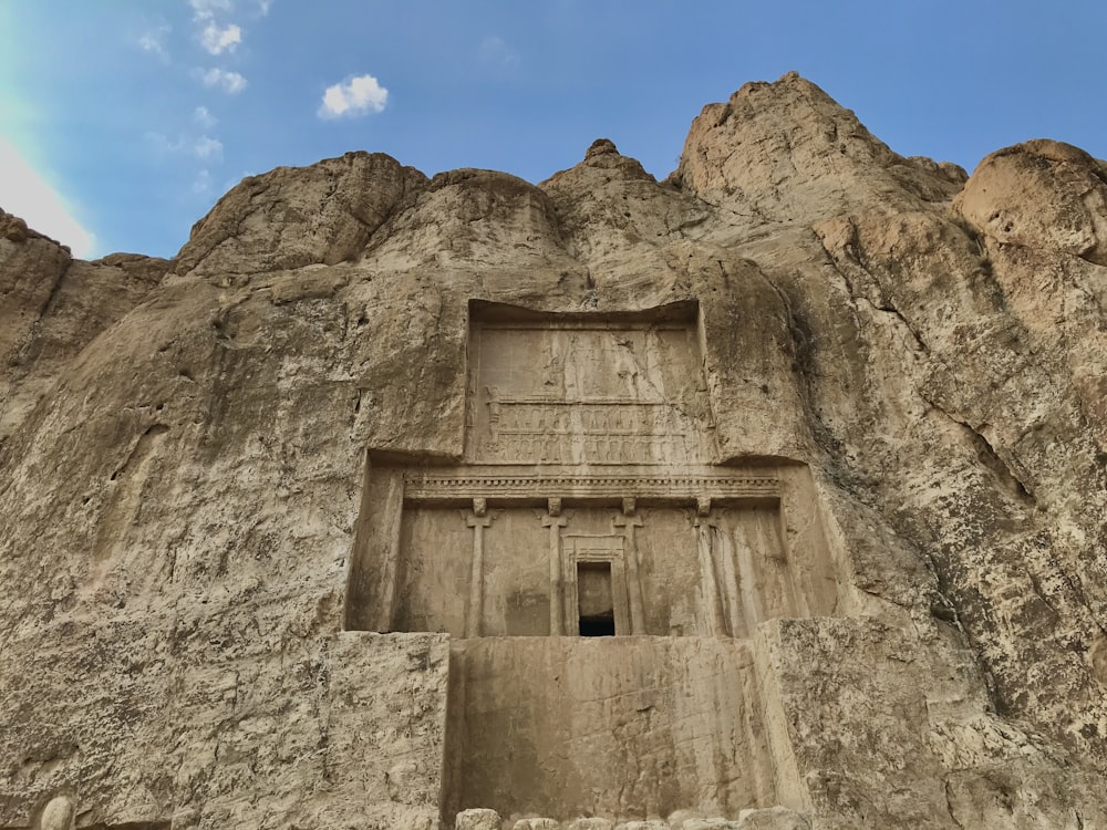 Bâtiment en béton brun sur une montagne rocheuse sous un ciel bleu pendant la journée