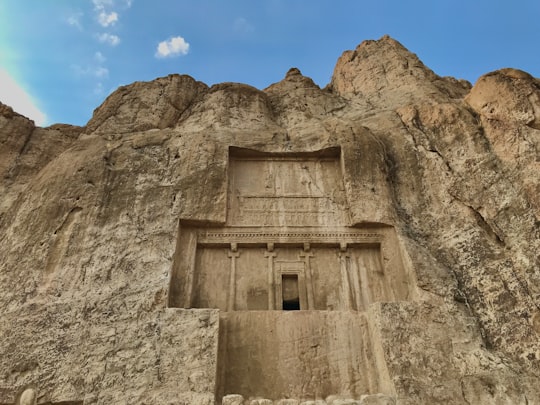 brown concrete building on rocky mountain under blue sky during daytime in Naqsh-e Rustam Iran