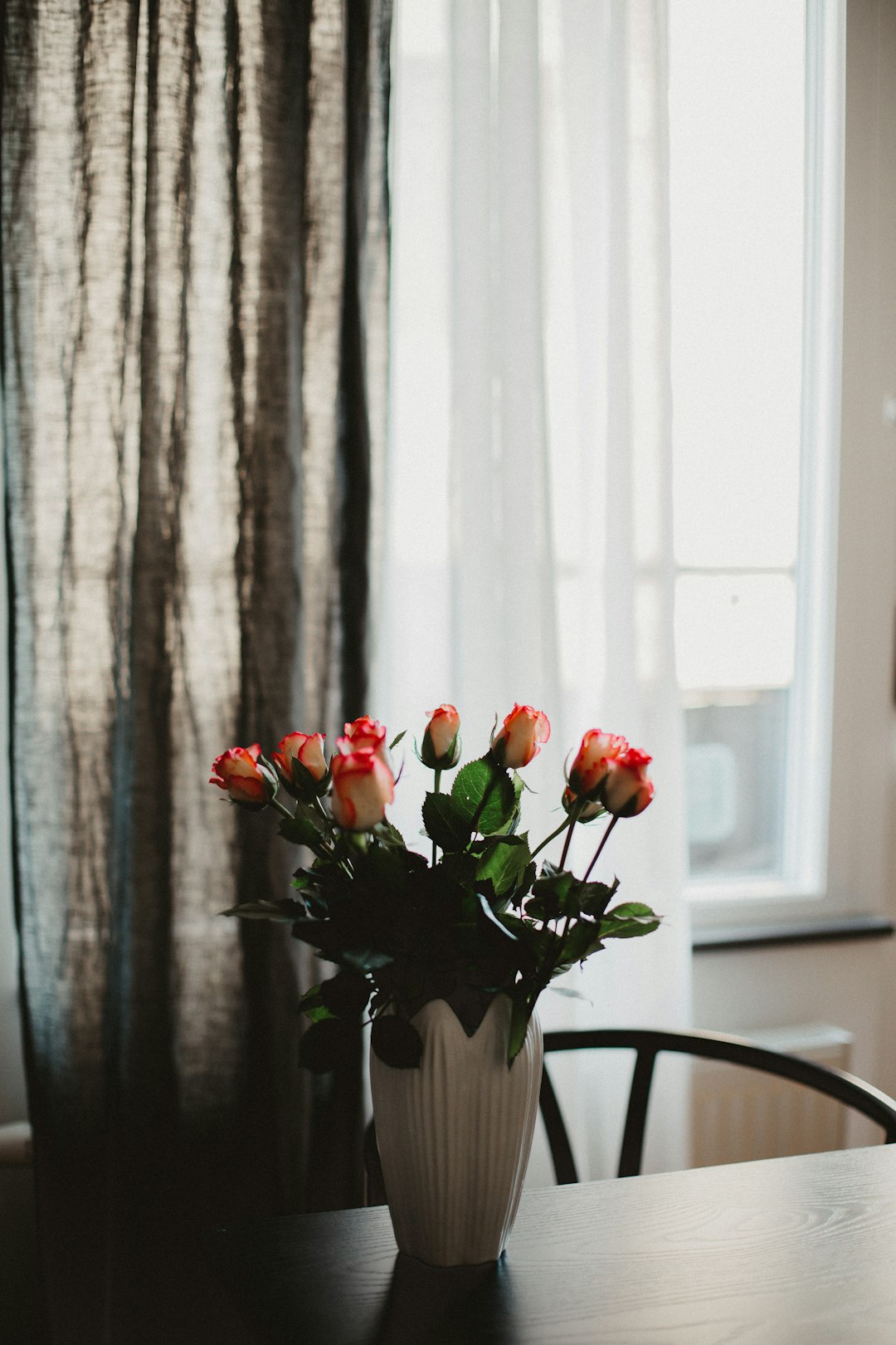 red roses in white vase on table