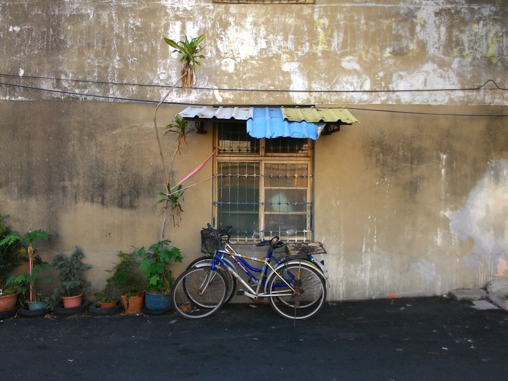 blue city bike parked beside brown concrete wall during daytime