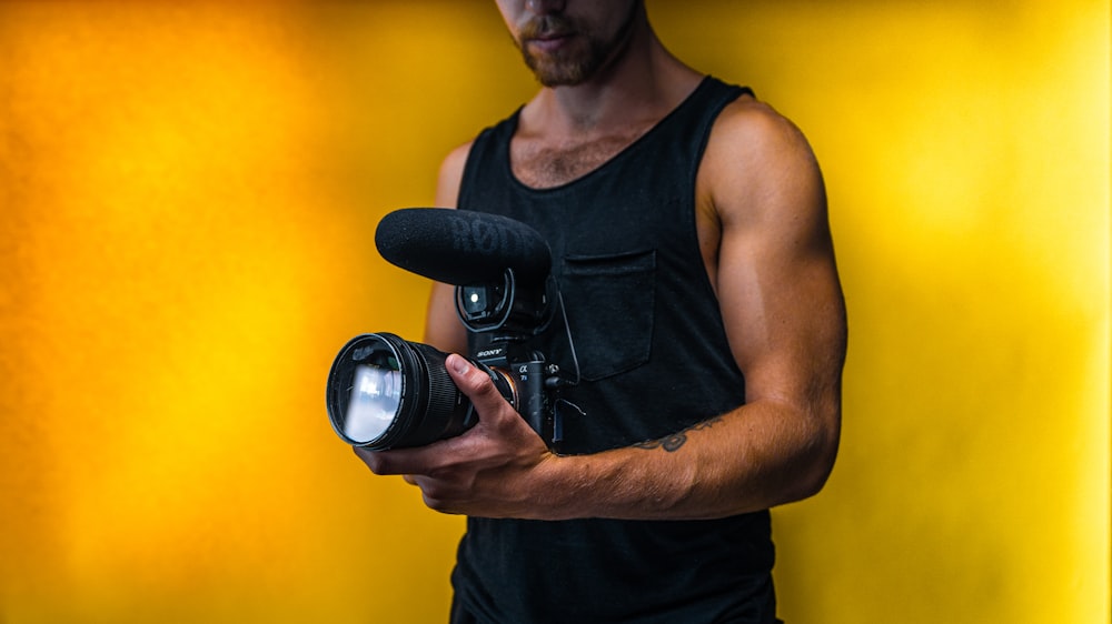 Mann in schwarzem Tanktop mit schwarzer DSLR-Kamera