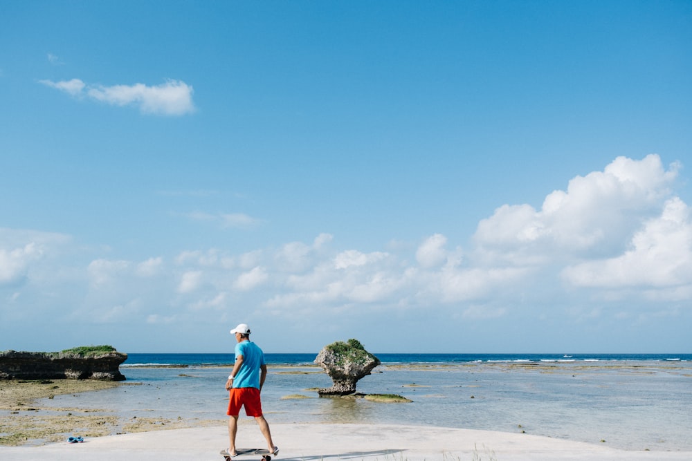 man in blue shorts walking on beach during daytime