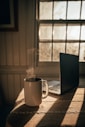 white ceramic mug beside silver macbook on table