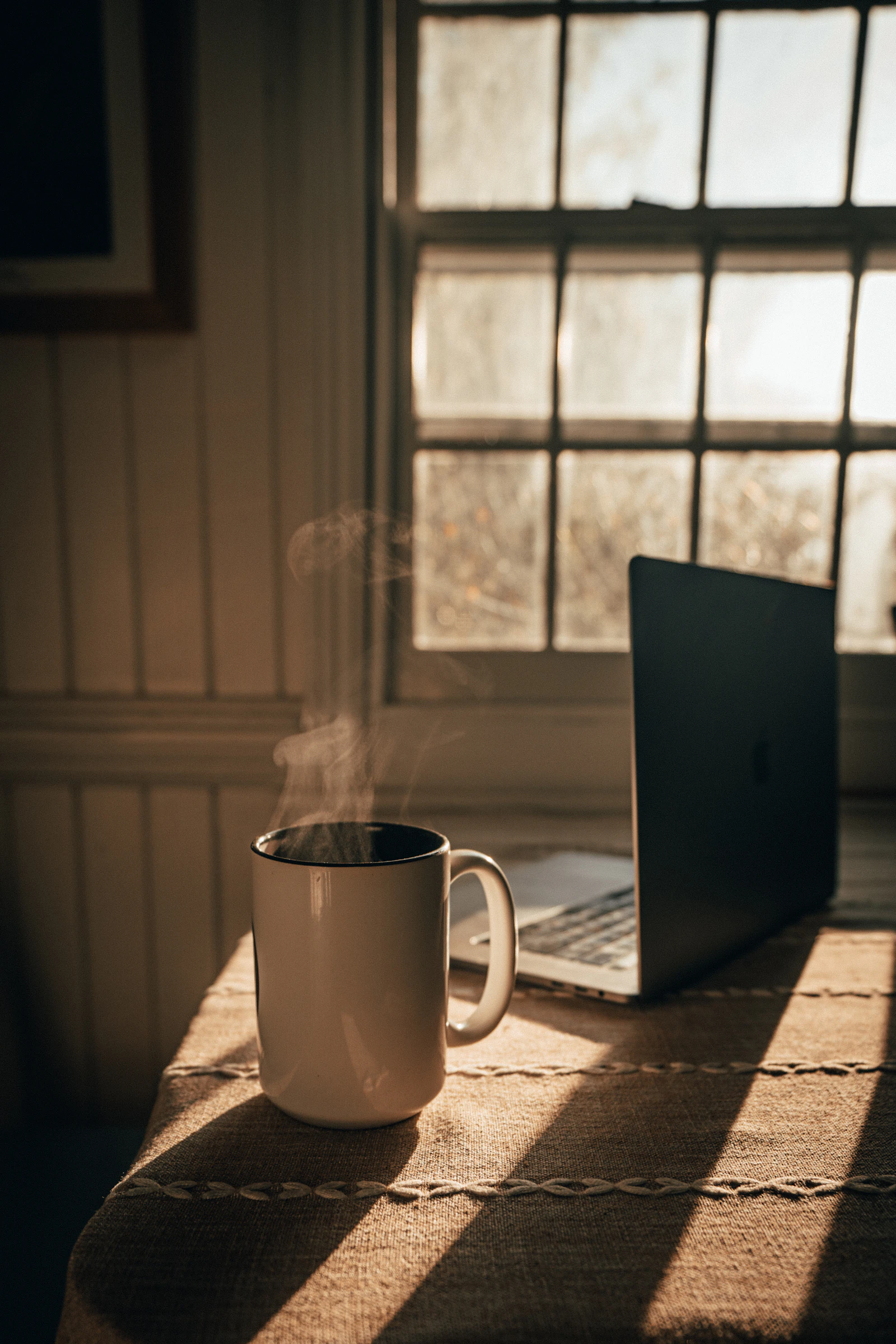 A quiet desk with a cup of coffee in soft morning light