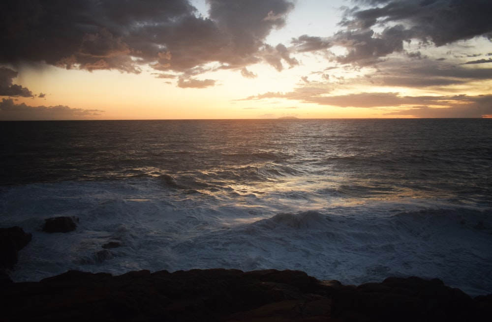 Olas del océano rompiendo contra las rocas durante la puesta de sol