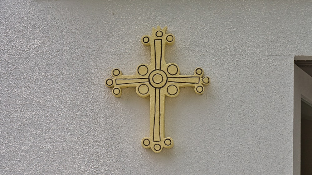 gold cross pendant on gray wall
