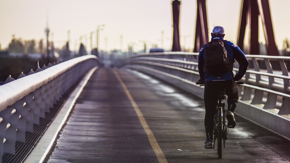 man in black jacket riding bicycle on road during daytime