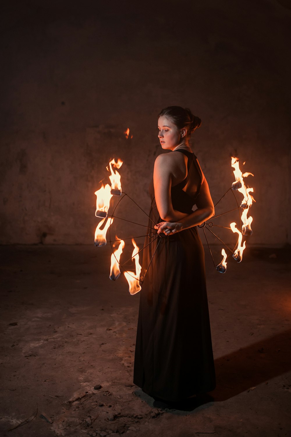 Mujer en vestido negro de tirantes finos sosteniendo fuego