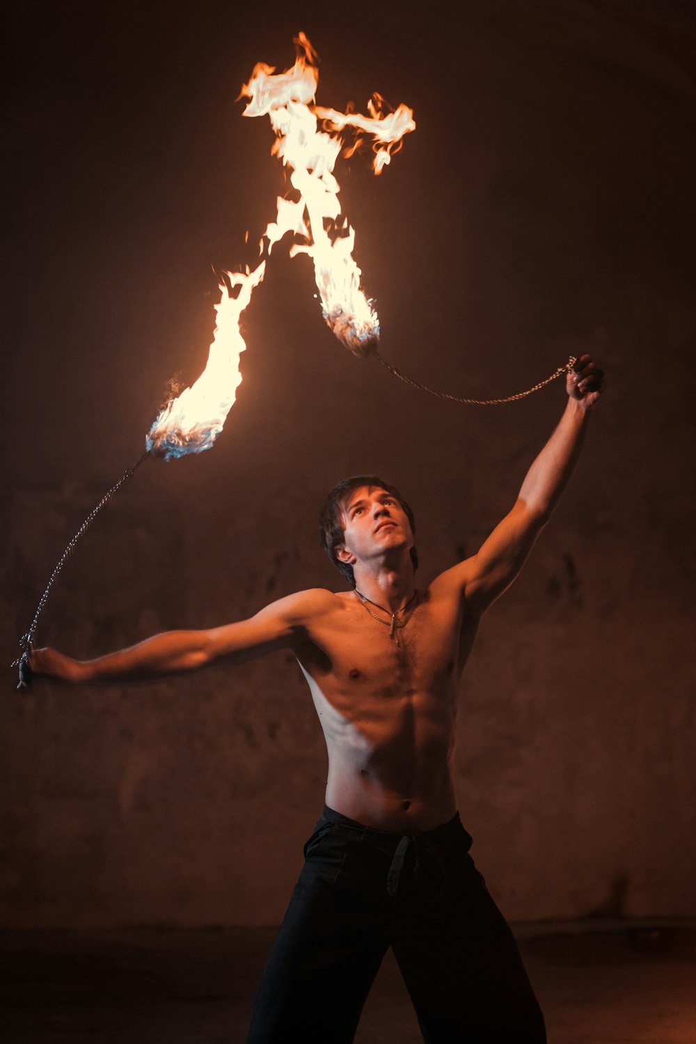 Hombre en topless en pantalones cortos negros sosteniendo fuego