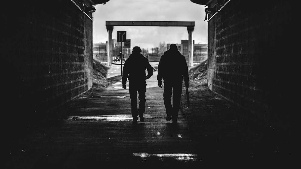 grayscale photo of man and woman walking on sidewalk