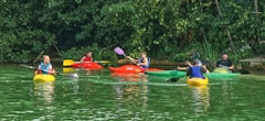 people riding on red kayak on river during daytime