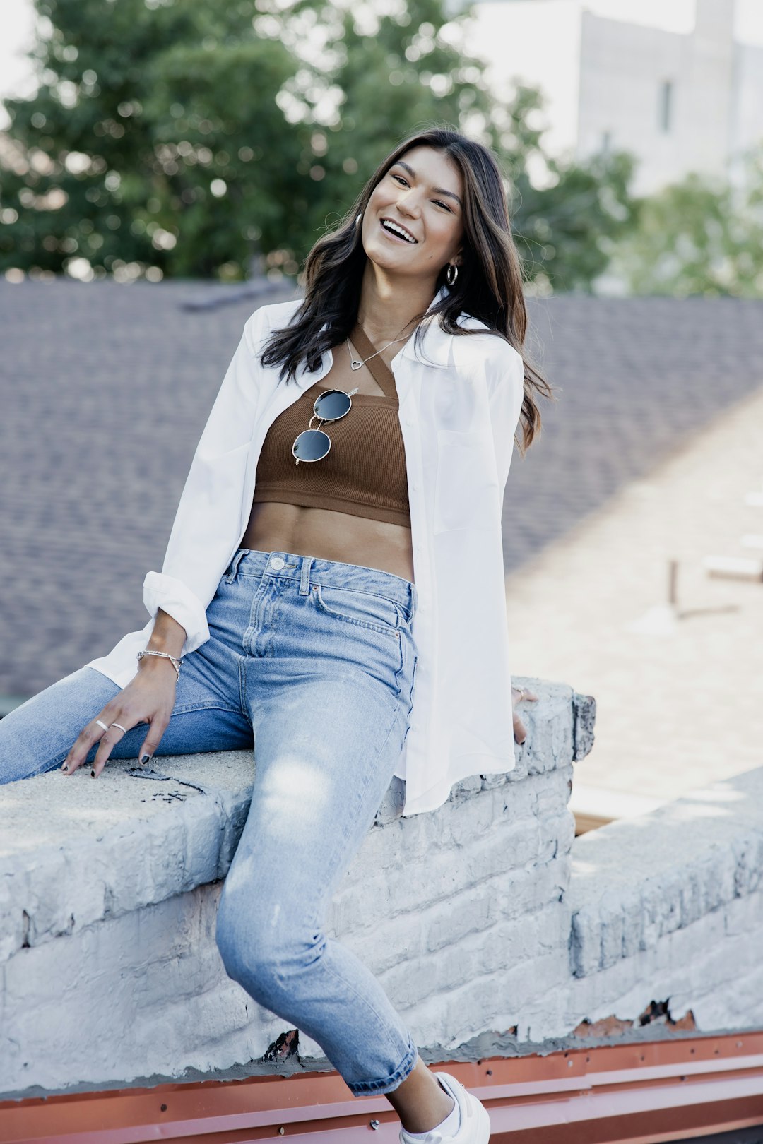 woman in white long sleeve shirt and blue denim jeans sitting on concrete bench during daytime