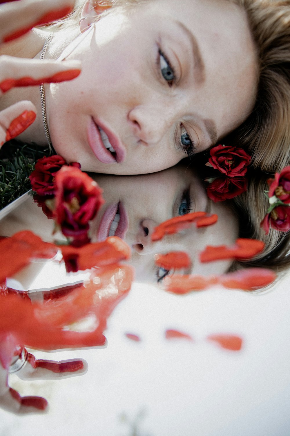 Frau mit roten Rosenblättern im Gesicht