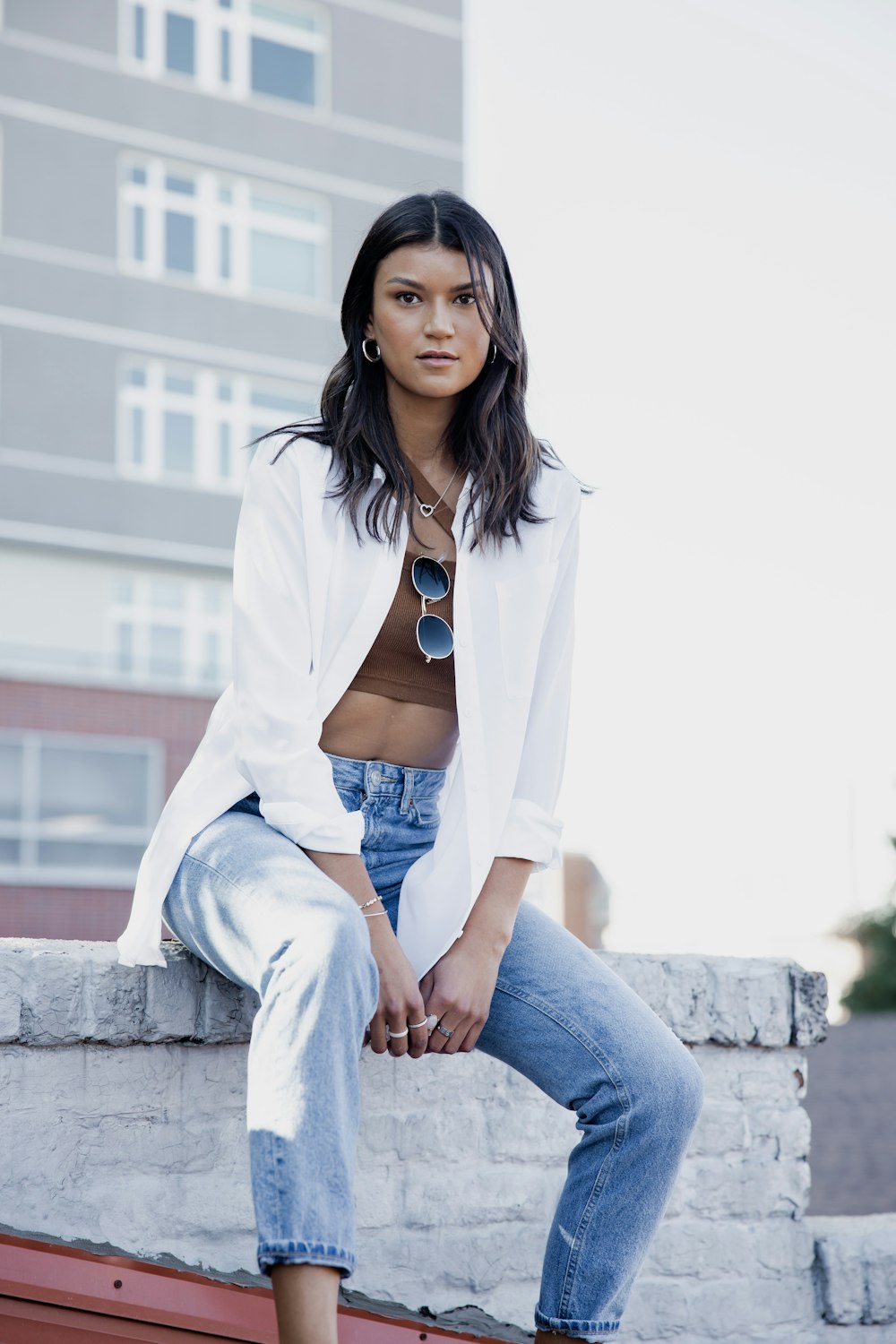 woman in white blazer and blue denim jeans sitting on concrete stairs